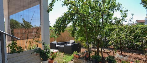 A modern outdoor patio with a seating area, potted plants, and a view of the surrounding garden.