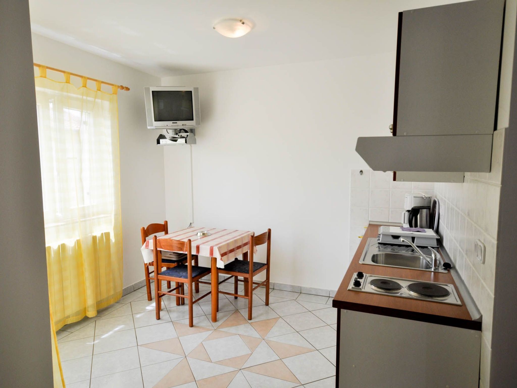A compact kitchen with a dining table, chairs, a TV, and a stove.