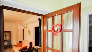 Una stanza con un letto, una sedia, un tavolino e una porta in legno decorata con un cuore.
