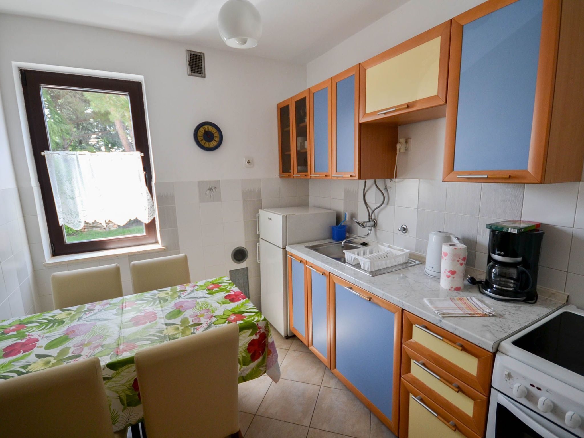 A compact kitchen with a dining area, featuring a refrigerator, stove, sink, and cabinets.