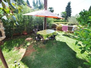 A patio with a table and chairs, surrounded by greenery and a small garden. - in Novigrad mit privatem Parkplatz by Interhome (Novigrad (Istra))