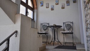 Una escalera con barandilla de metal, un arco de ladrillo y una pared con varias pequeñas pinturas.
