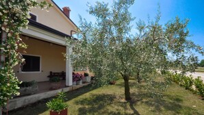 Ein Haus mit Veranda, Rasen und Baum.