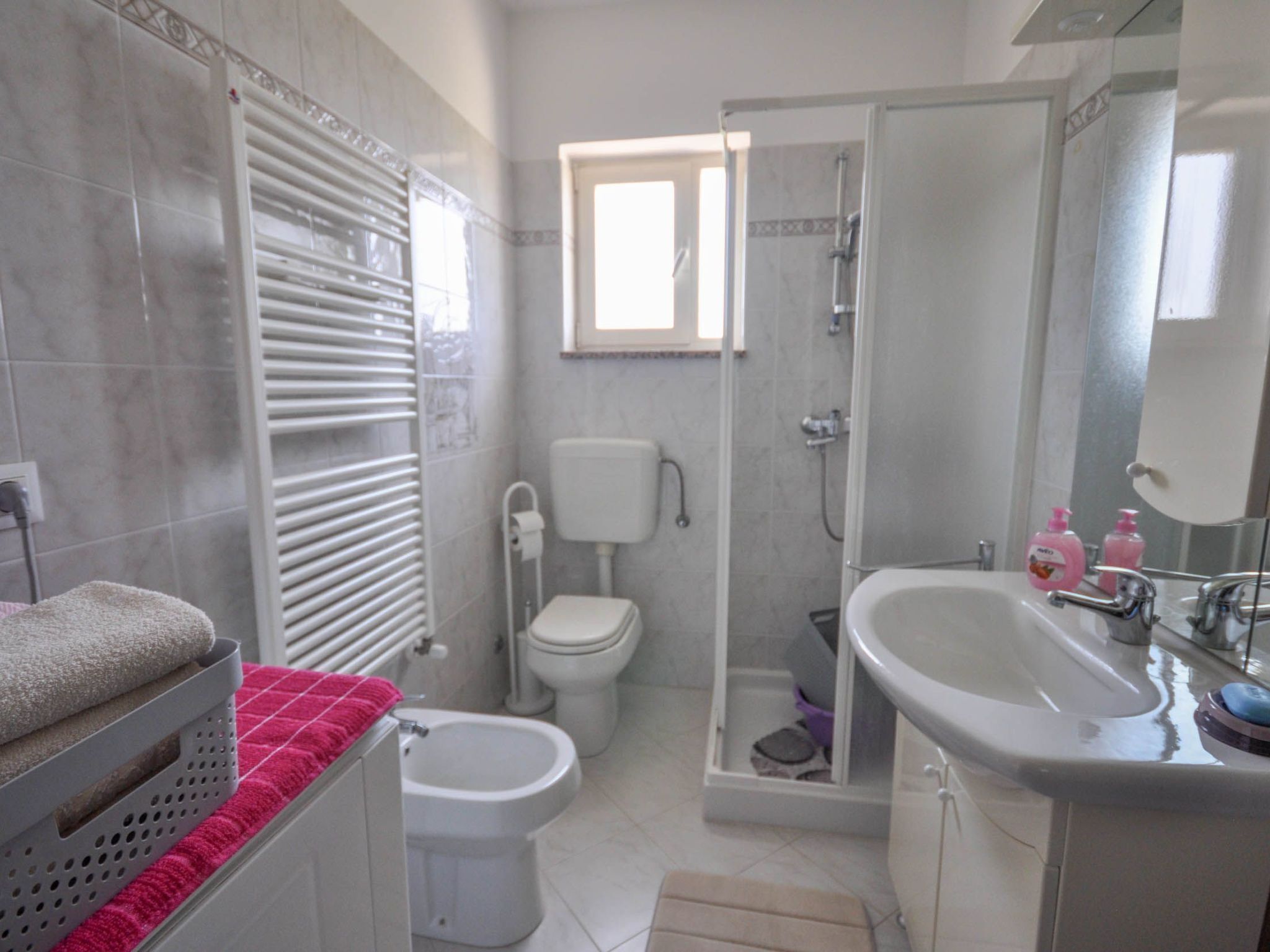 Een badkamer met toilet, hygiëneschuimer, douche en wastafel.
