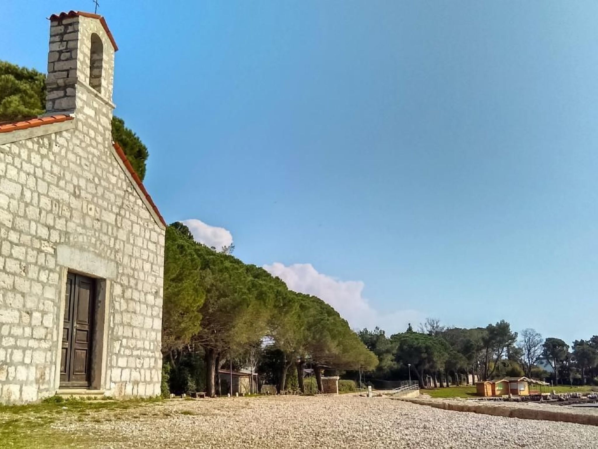 A stone building with a red-tiled roof, a chimney, and a door.