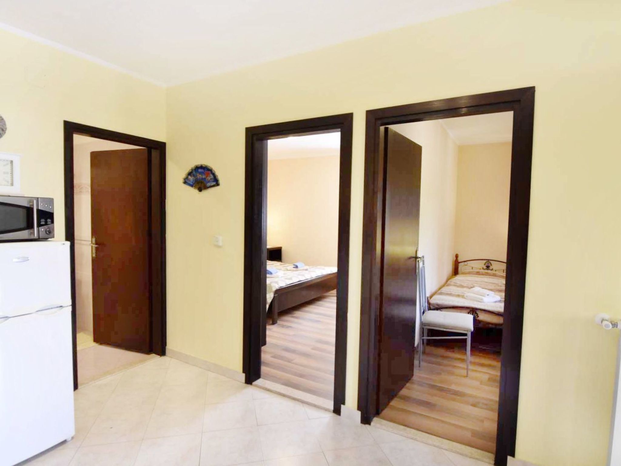 Een kleine kamer met een bed, een bureau en een magnetron.