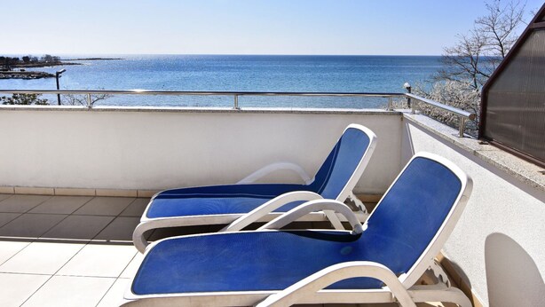 A balcony with two blue lounge chairs facing a clear blue sea. - Wohnung in Zambratija mit Schöner Terrasse by Interhome (Umag/Zambratija)