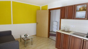 A compact kitchen with wooden cabinets, a glass table, and a yellow accent wall. - Wohnung in Zambratija mit Schöner Terrasse by Interhome (Umag/Zambratija)