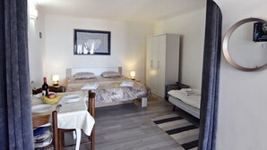 Een hotelkamer met een bed, een nachtkastje met lamp, een stoel, een eettafel met stoel, een garderobe en een spiegel.
