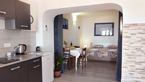 Een compacte hotelkamer met een kitchenette, een eethoek en een bed.