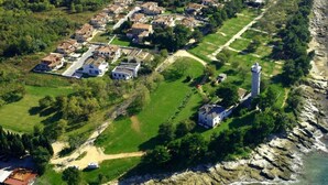 An aerial view of a coastal residential area with houses, a lighthouse, and a rocky shoreline. - Apartment Elia 1 by Interhome (Umag/Savudrija)