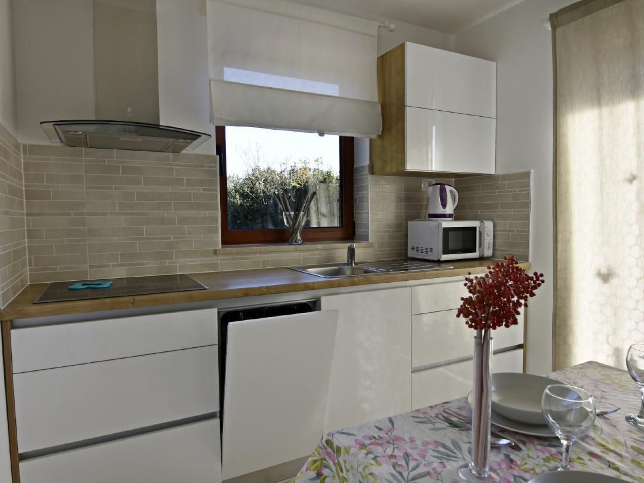 A compact kitchen with a window, a microwave, and a sink.
