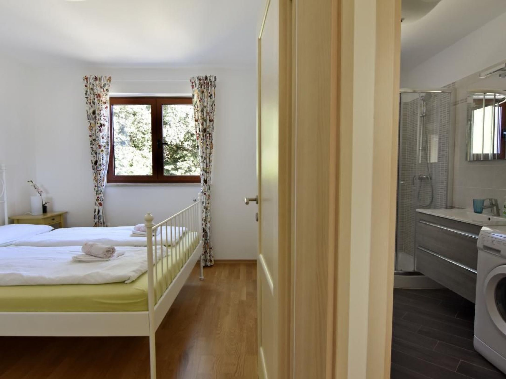 Une chambre à coucher avec un lit, une fenêtre avec des rideaux et une vue sur l’extérieur.