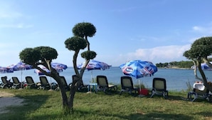 Un espace aménagé avec des parasols et des chaises, situé au bord de la plage et offrant une vue sur une mer calme.