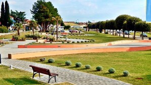 Ein Park mit einem gepflasterten Weg, einer Bank und ordentlich gestutztem Gras.
