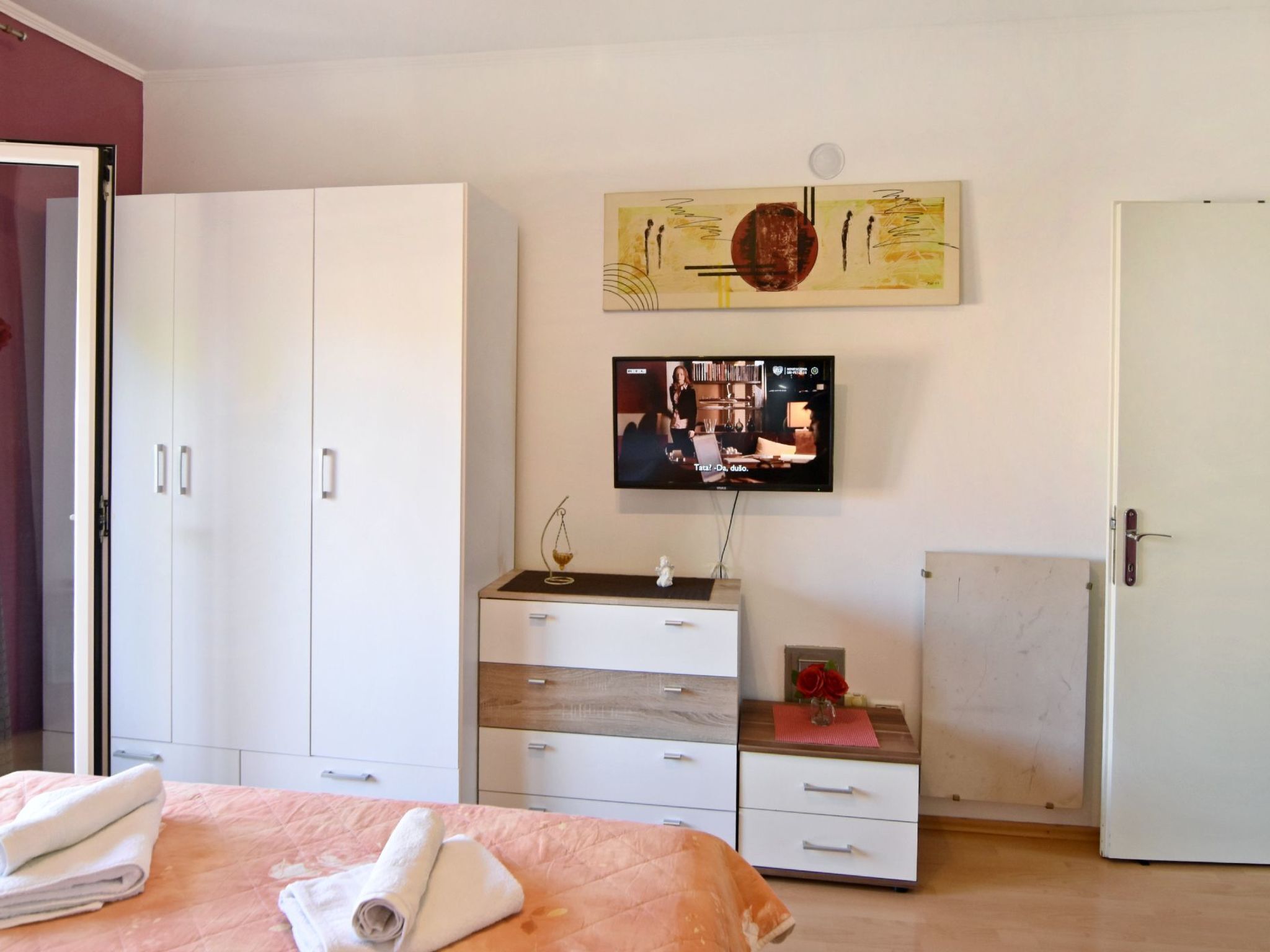 Makuuhuoneessa on sänky, vaatekaappi, televisio ja seinällä taulu.