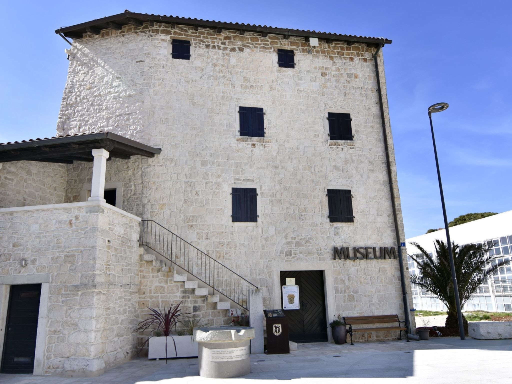 A stone building with a staircase leading to a door marked "MUSEUM".
