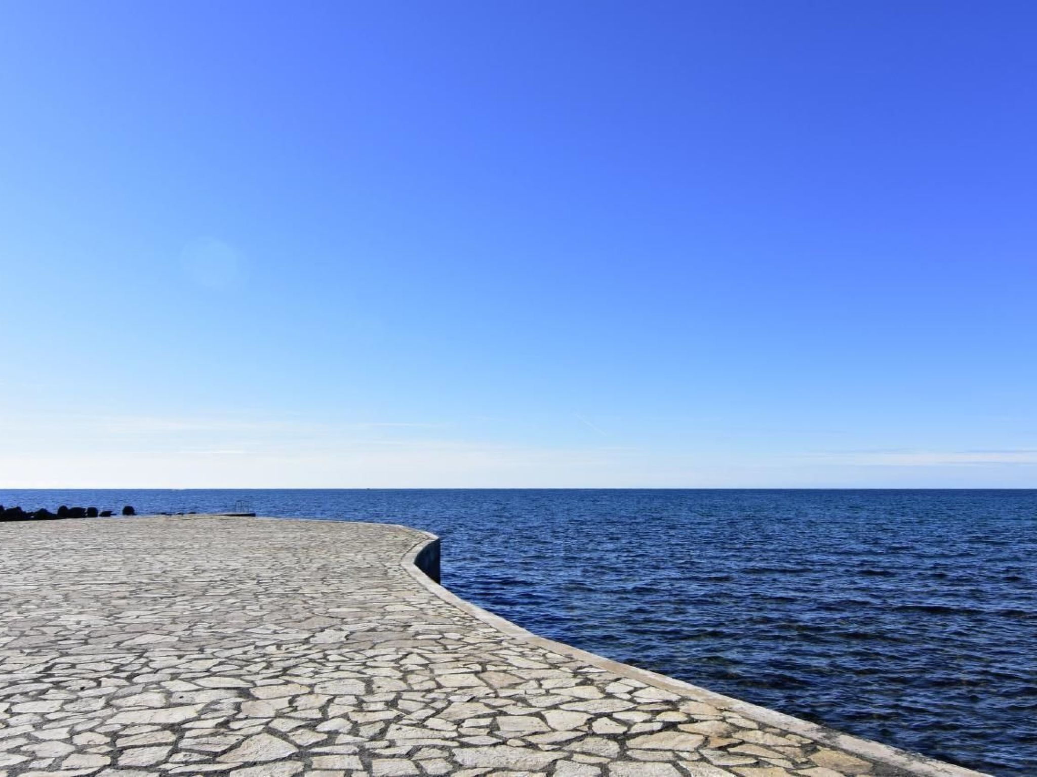 A paved waterfront walkway with a clear view of the sea.