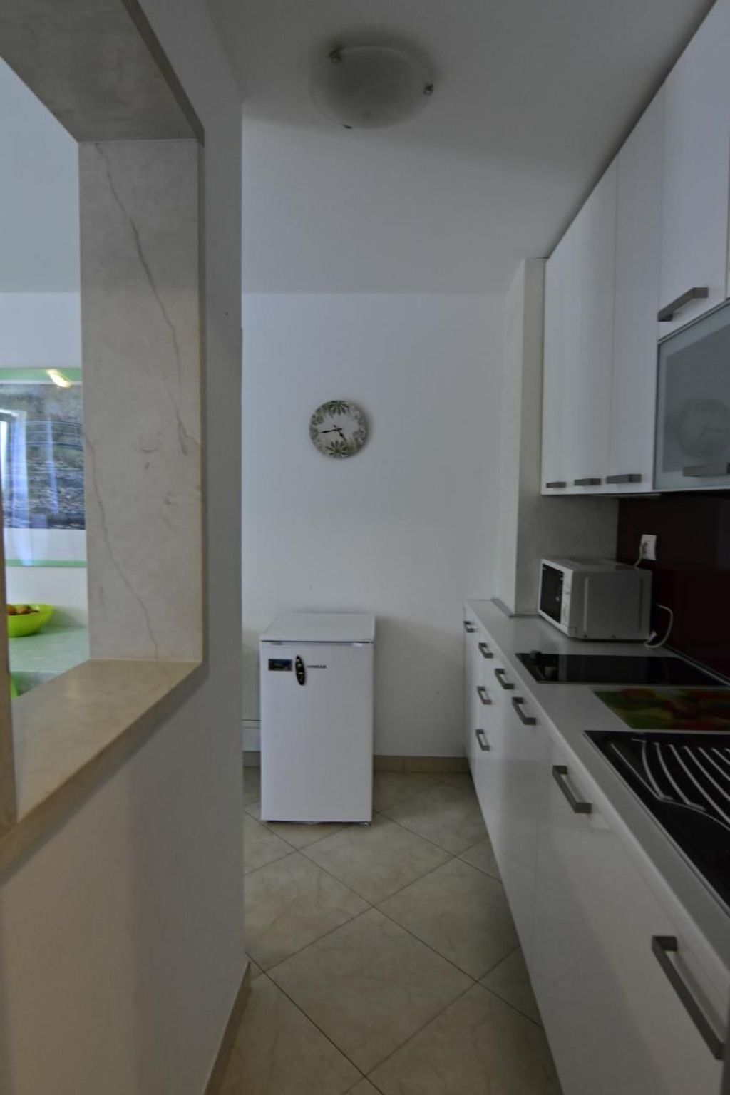 A compact kitchen with white cabinets, a microwave, and a small refrigerator.