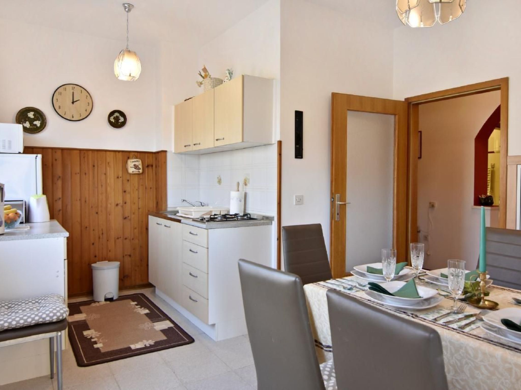 A modern kitchen with white cabinets, a stove, and a dining area with a table set for two.