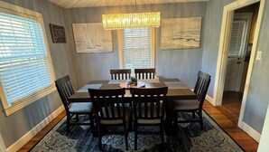 Un comedor con una mesa y sillas de madera, un tapete estampado y obras de arte en las paredes.