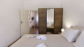 A hotel room with a bed, a bedside table with a book and towels, a mirror, and a view of a bathroom with a shower and toilet. - TATJANA MOELA by Interhome (Umag)