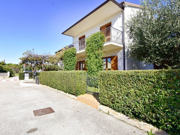 A two-story residential building with a balcony, a gated entrance, and a well-maintained hedge. - LINO B4 by Interhome (Umag)