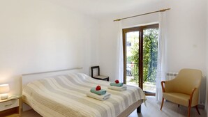 Une chambre à coucher comprenant un lit, une chaise, une table de chevet et une fenêtre donnant sur un paysage verdoyant.