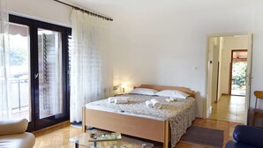 Ein Schlafzimmer mit einem Bett, einem Glastisch, einer Couch und einer Tür, die auf einen Balkon führt.