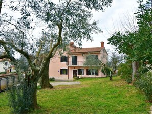 A two-story house with a tiled roof, surrounded by a grassy yard and trees. - Wohnung in Valica mit Großem Garten by Interhome (Umag)