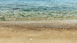 Una playa con aguas cristalinas y poca profundidad, y una orilla arenosa.