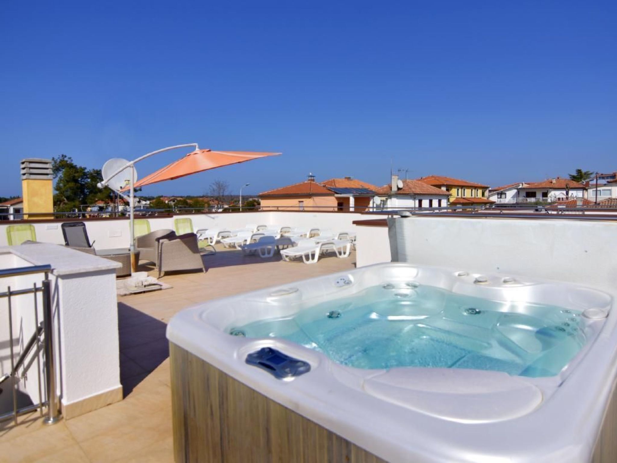 Terraço no telhado com hidromassagem, espreguiçadeiras e vista desobstruída do bairro.