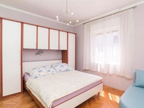 A bedroom with a bed, a wardrobe, a ceiling light, and a window with curtains. - Große Wohnung in Umag mit Kleinem Balkon by Interhome (Umag)