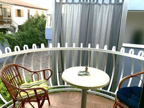 A balcony with wicker chairs, a small round table, and a view of a building and greenery. - Große Wohnung in Umag mit Kleinem Balkon by Interhome (Umag)