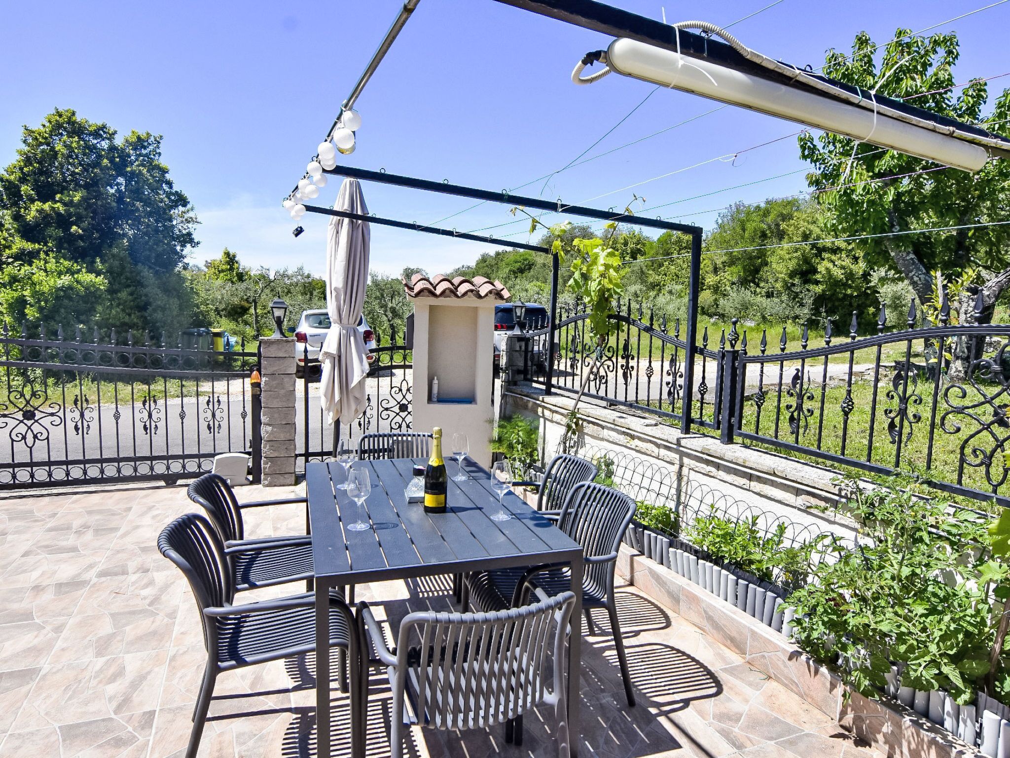 An outdoor patio with a table and chairs, a bottle of champagne, and a decorative umbrella.