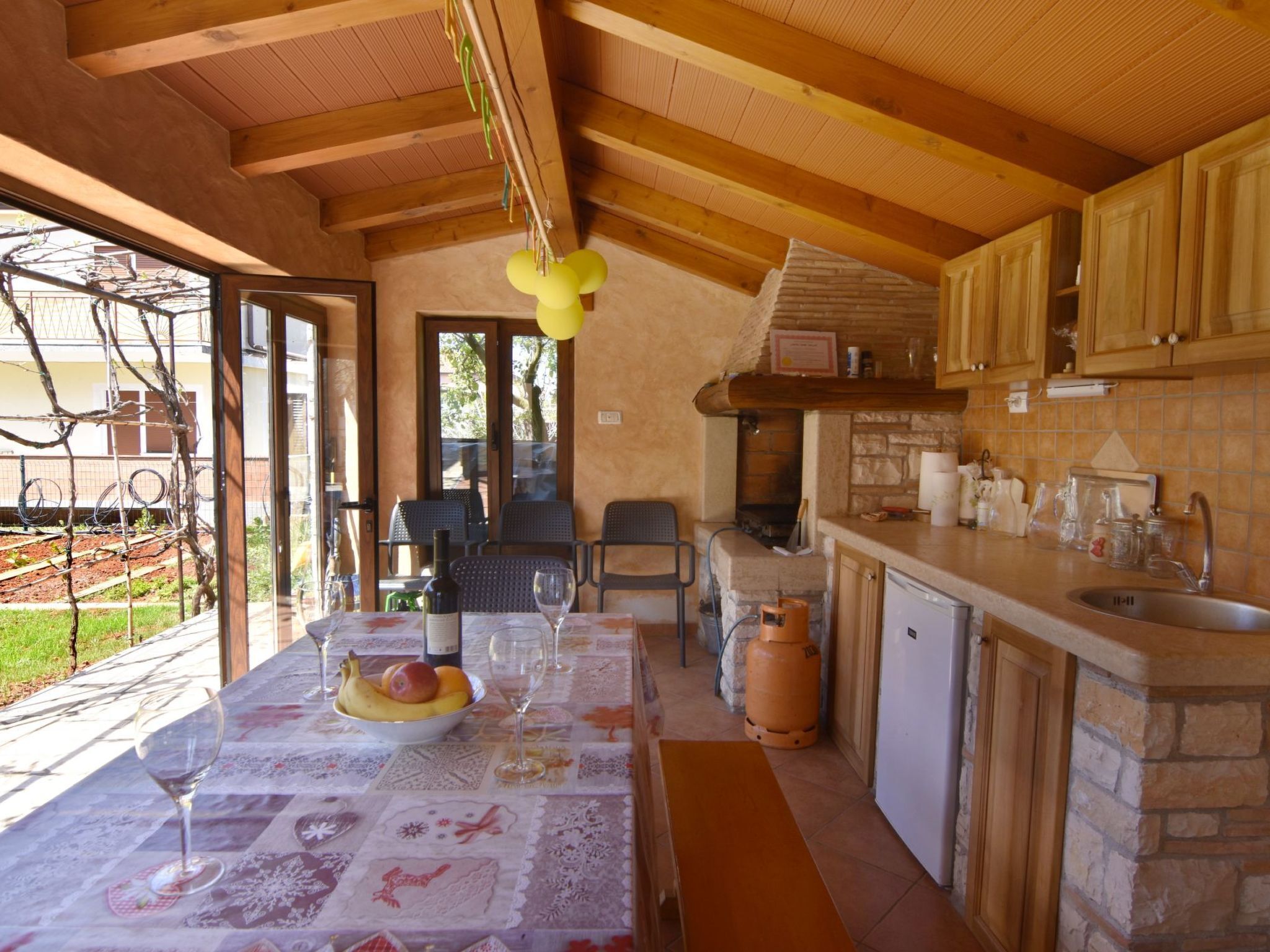A rustic kitchen with wooden beams, a stone countertop, and a dining area with a table set for two.