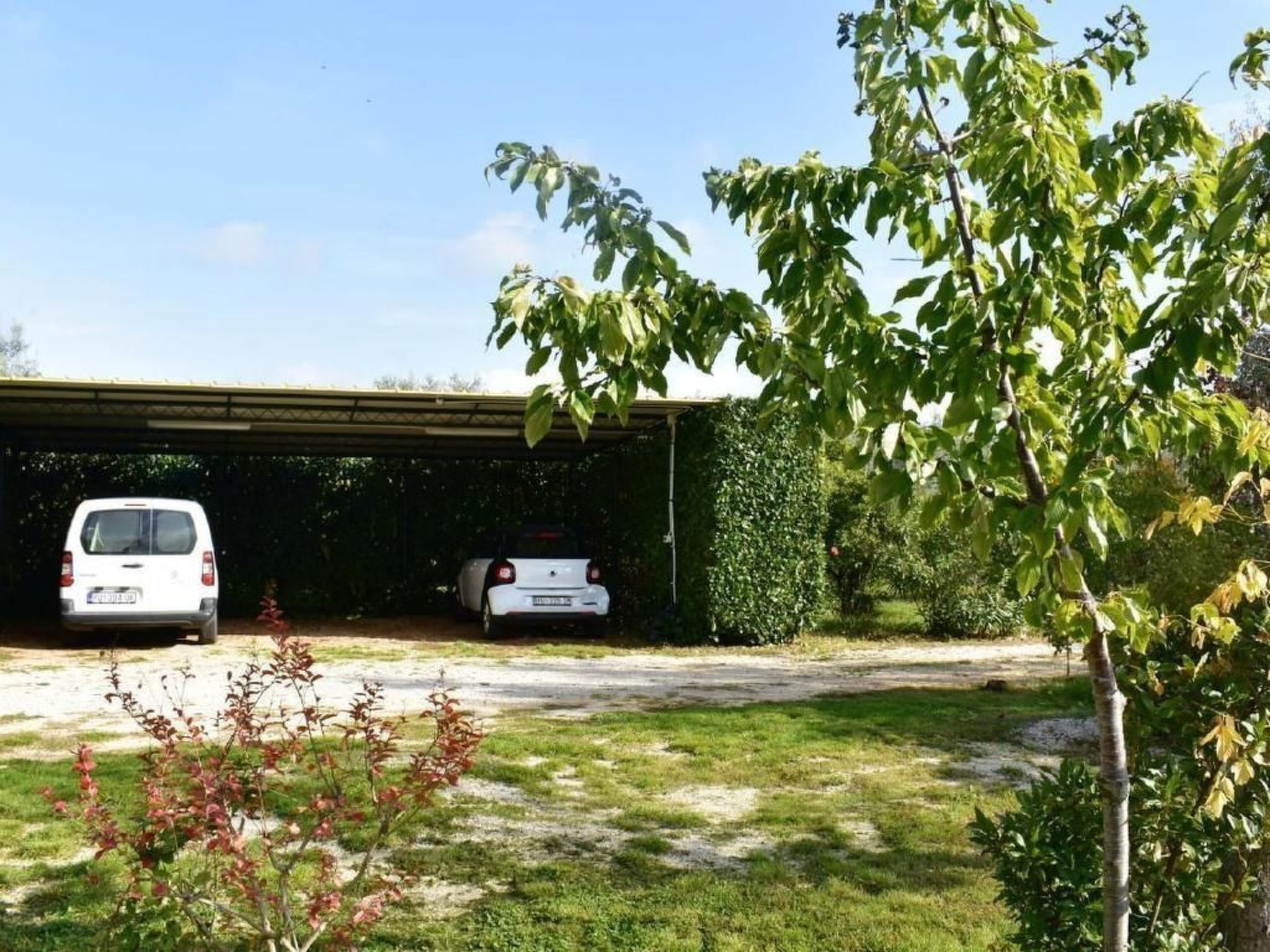 Un espace de stationnement couvert où deux voitures blanches sont garées sous un abri.