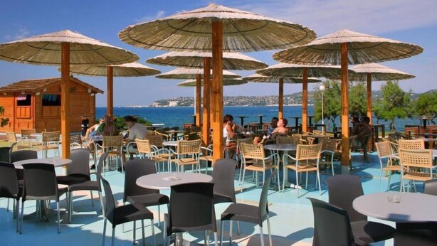 Ein Restaurant direkt am Strand mit Terrassenplätzen, Sonnenschirmen und Meerblick.