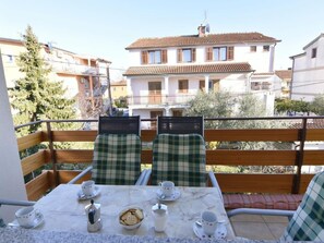 A balcony with two checkered chairs, a table with cups and a teapot, and a view of a building with a tiled roof. - ANA Ž. 2 VELIKI by Interhome (Umag)