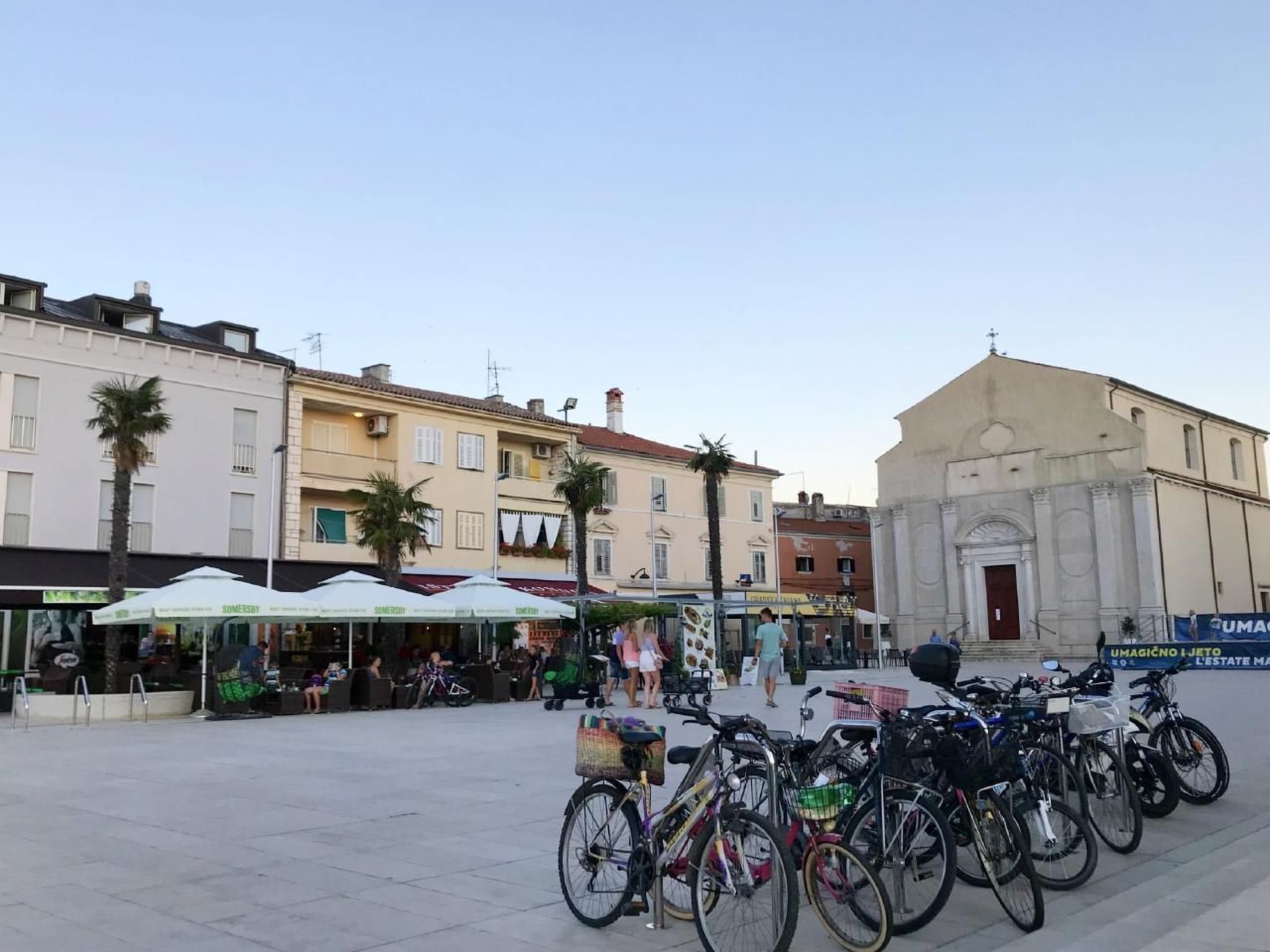 Una plaza pública con una fila de bicicletas estacionadas frente a un edificio de arquitectura clásica.