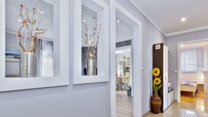 Een moderne hotelgang met een gepolijste vloer, ingelijste kunstwerken en een vaas met zonnebloemen.