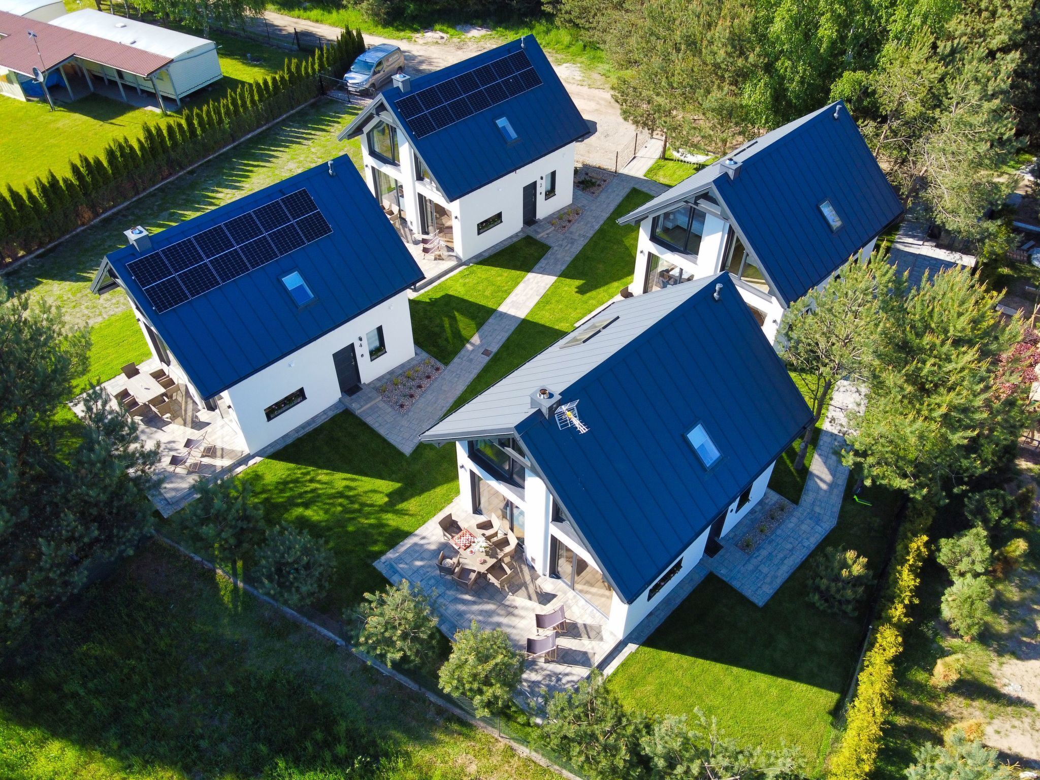 Una casa moderna con paneles solares, césped cuidado y una vista despejada del entorno.