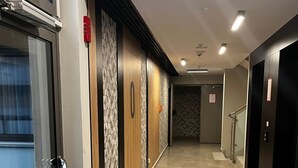 A hotel corridor with a glass door entrance, a patterned wall, and a tiled floor. - Apartment Sky by Interhome (Kolobrzeg)
