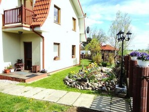 A two-story house with a balcony, a garden with a variety of plants, and a wooden fence. - mit Terrasse by Interhome (Rewal)