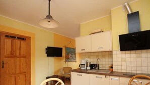 Une cuisine compacte avec des meubles en bois, un four à micro-ondes encastré et un téléviseur fixé au-dessus du plan de travail.