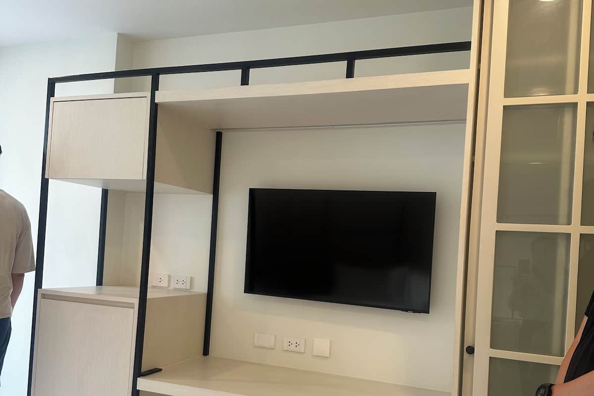 A bunk bed with a TV mounted above it, a cabinet with frosted glass doors, and a marble-patterned floor.