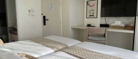 A hotel room with two beds, a desk, a television, and a bathroom visible through an open door.