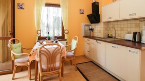 Une cuisine compacte avec un coin repas, comprenant une table avec des chaises, une fenêtre avec des rideaux et les appareils de cuisine de base.