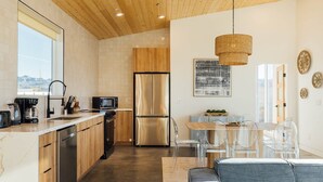 Eine moderne Küche mit Holzausstattung, Edelstahlgeräten und einem Essbereich mit transparenten Stühlen und einem Tisch.