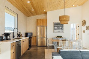Eine moderne Küche mit Holzausstattung, Edelstahlgeräten und einem Essbereich mit transparenten Stühlen und einem Tisch.
